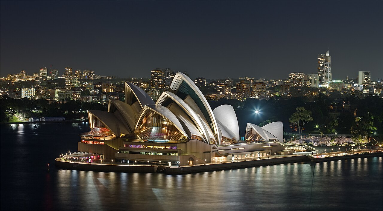 Sydney Opera House illuminated at dusk along Sydney Harbour